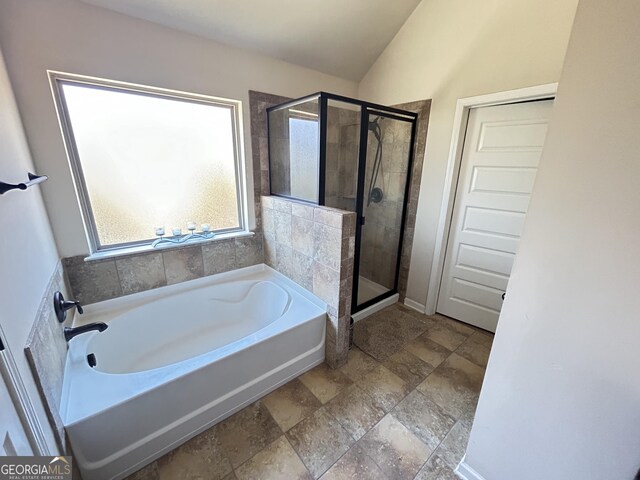 bathroom featuring a bath, lofted ceiling, and a shower stall