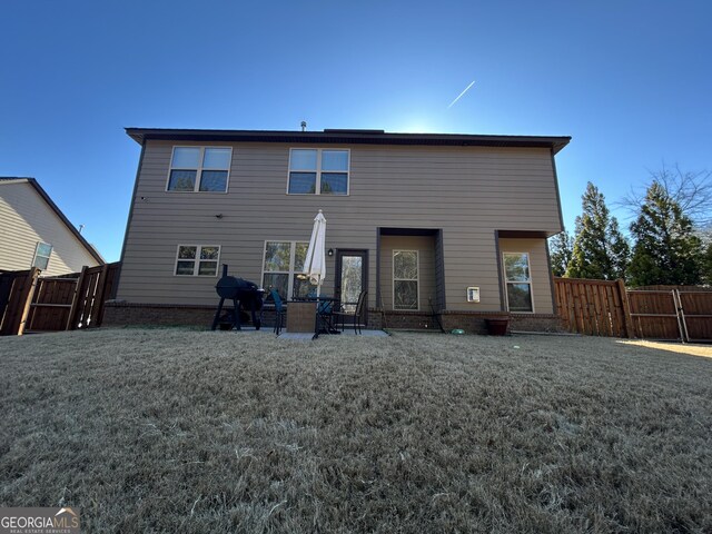 back of house with a patio area, a gate, fence, and a yard
