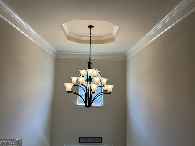 details featuring an inviting chandelier, a raised ceiling, and crown molding
