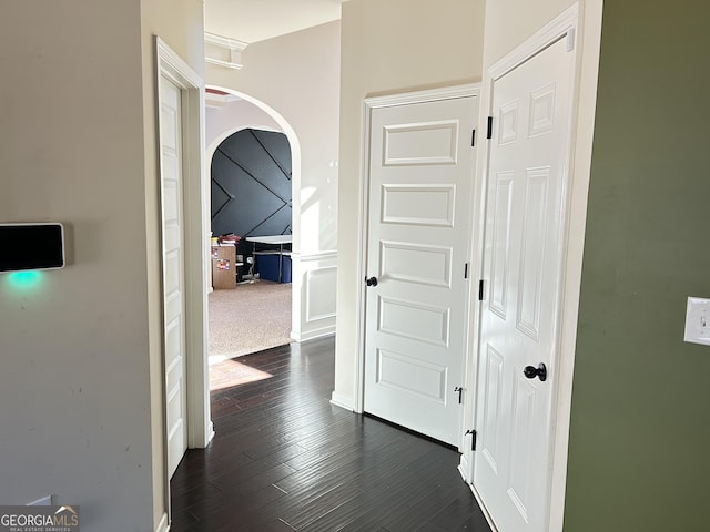 hallway featuring arched walkways and dark wood-type flooring