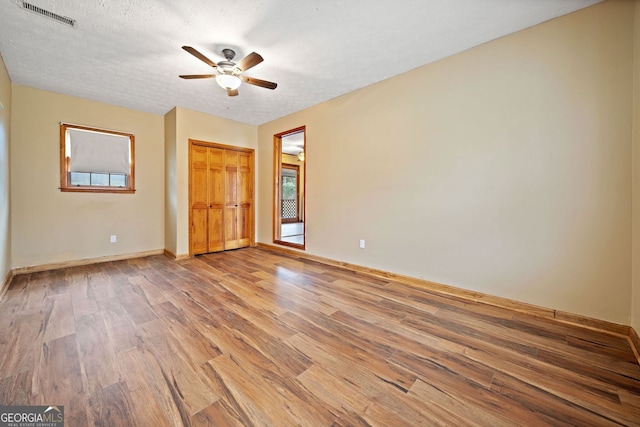 unfurnished bedroom featuring visible vents, light wood-style flooring, ceiling fan, a textured ceiling, and baseboards