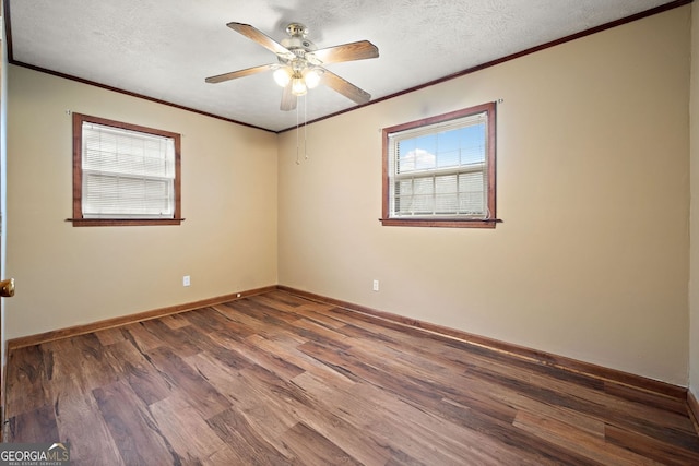 spare room featuring a textured ceiling, wood finished floors, a ceiling fan, baseboards, and ornamental molding