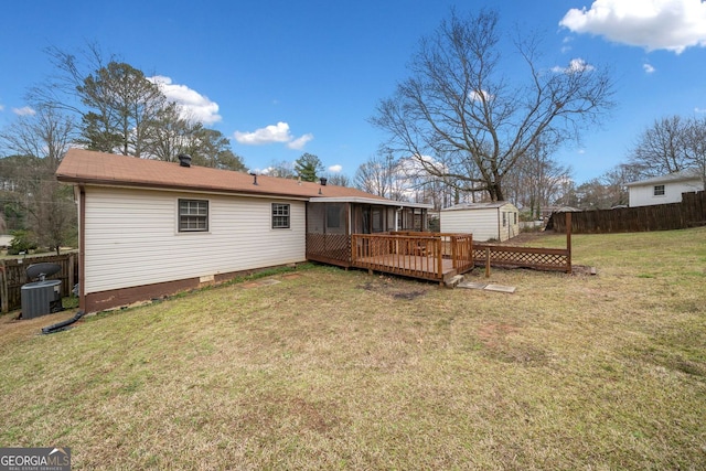 rear view of house featuring an outbuilding, a yard, fence, a shed, and a wooden deck