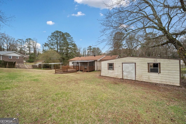 view of yard featuring an outdoor structure, a wooden deck, and fence