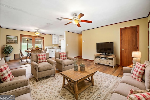 living room with ceiling fan, visible vents, light wood-style flooring, and baseboards