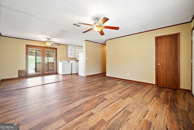 unfurnished living room featuring baseboards, ceiling fan, wood finished floors, washer and dryer, and french doors