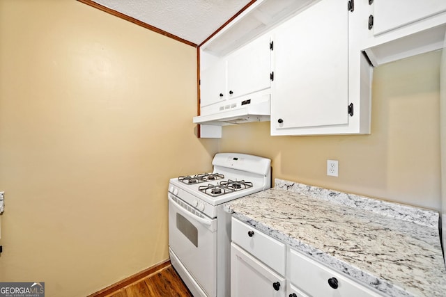 kitchen featuring white range with gas cooktop, dark wood-style flooring, a textured ceiling, under cabinet range hood, and white cabinetry