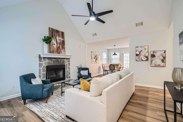 living area with high vaulted ceiling, visible vents, and wood finished floors