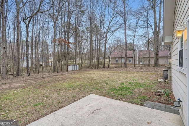 view of yard featuring a patio area, central AC, and an outbuilding