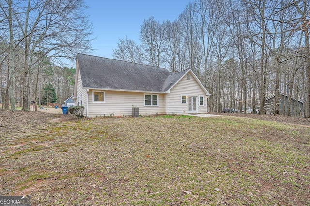 exterior space with central AC, roof with shingles, a patio area, and a front yard