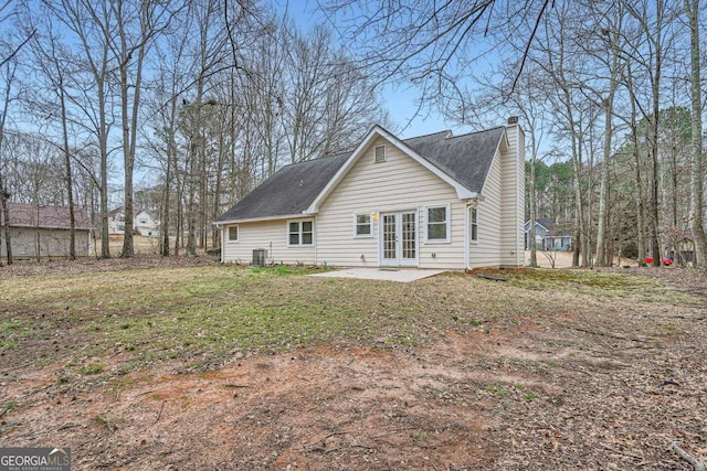 rear view of property featuring a shingled roof, french doors, a patio, a chimney, and a yard