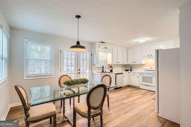 kitchen featuring white appliances, white cabinets, light countertops, light wood-type flooring, and under cabinet range hood