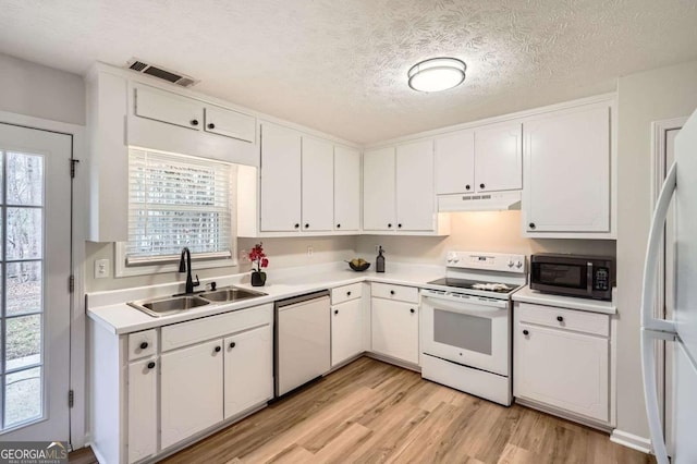 kitchen with white appliances, white cabinets, a sink, and under cabinet range hood