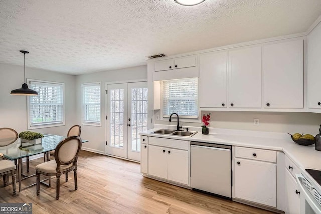 kitchen with white cabinets, dishwasher, light wood-style flooring, french doors, and a sink