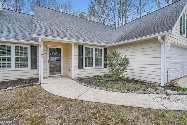 property entrance featuring a shingled roof and a garage