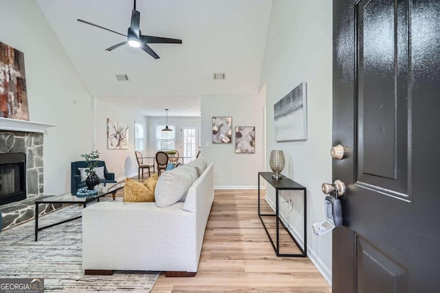 living area featuring a fireplace, visible vents, a ceiling fan, light wood-type flooring, and baseboards