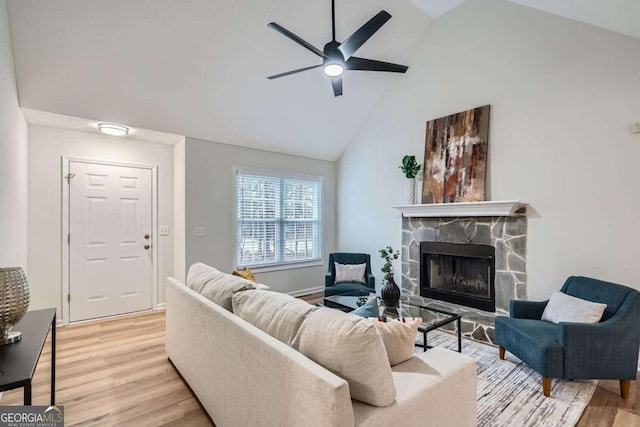 living area with ceiling fan, high vaulted ceiling, light wood-type flooring, and a fireplace