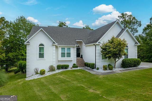 ranch-style home featuring a front lawn, an attached garage, and stucco siding