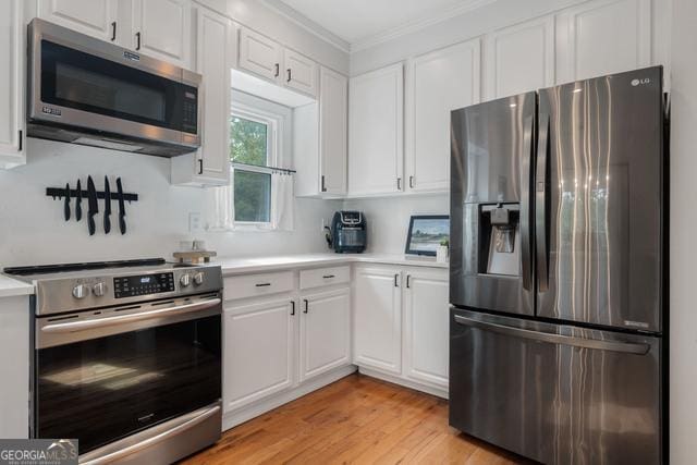 kitchen featuring stainless steel appliances, light countertops, light wood-style flooring, and white cabinetry