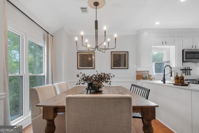 dining room with light wood finished floors, a wealth of natural light, and crown molding