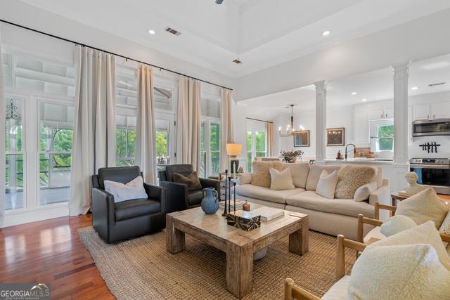 living room featuring decorative columns, visible vents, wood finished floors, a notable chandelier, and recessed lighting