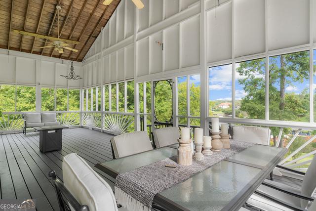 sunroom / solarium featuring lofted ceiling, wooden ceiling, and a ceiling fan