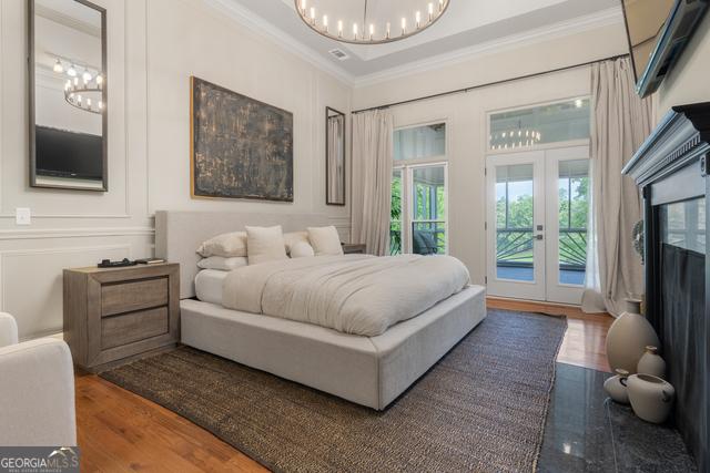 bedroom with access to exterior, french doors, crown molding, and an inviting chandelier