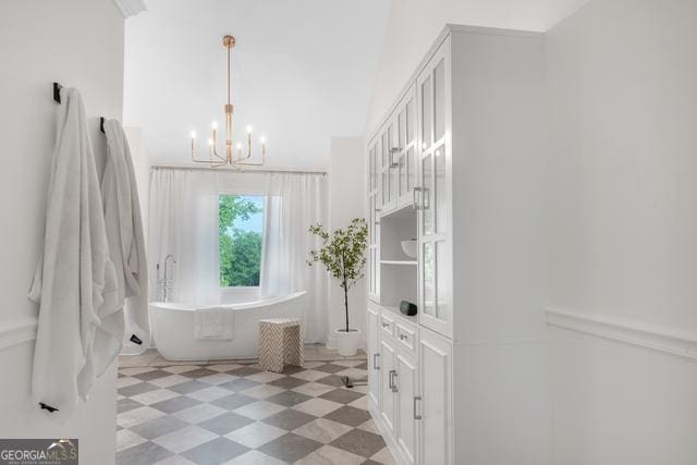 bathroom featuring a notable chandelier, a soaking tub, and tile patterned floors