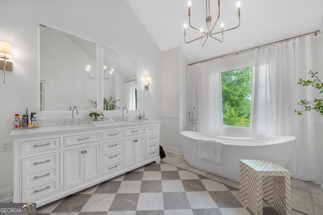 full bath featuring vaulted ceiling, double vanity, a sink, and a notable chandelier