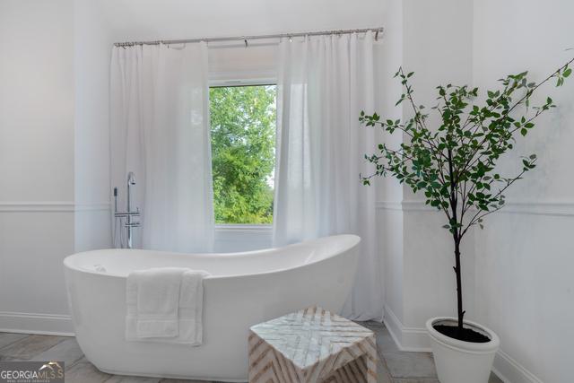 full bath with a freestanding bath, a wealth of natural light, and baseboards