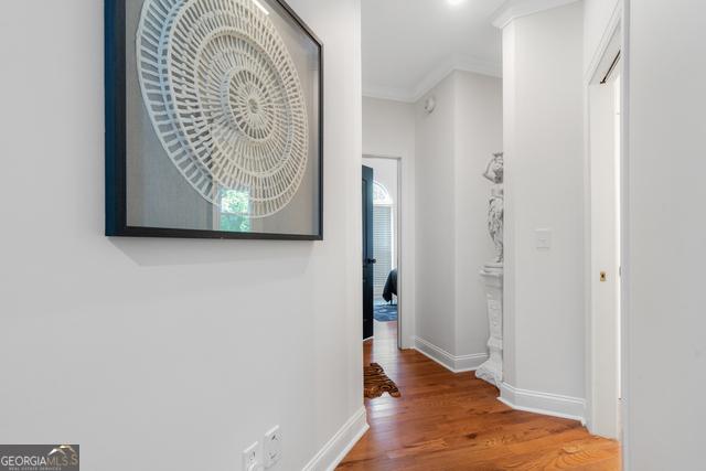 hall featuring ornamental molding, baseboards, and wood finished floors