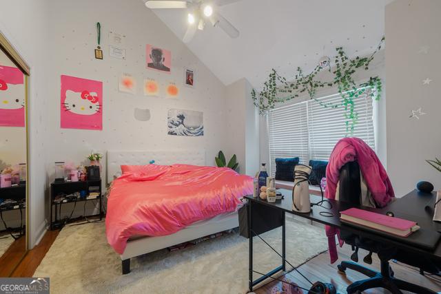 bedroom with high vaulted ceiling, a ceiling fan, and wood finished floors