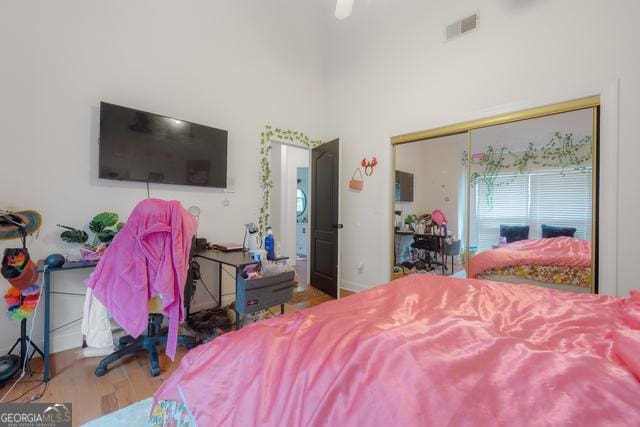 bedroom with a closet, visible vents, ceiling fan, and wood finished floors