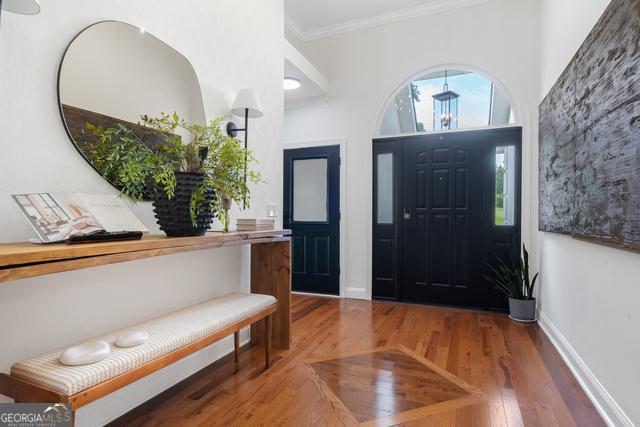 entrance foyer featuring baseboards, wood finished floors, and crown molding