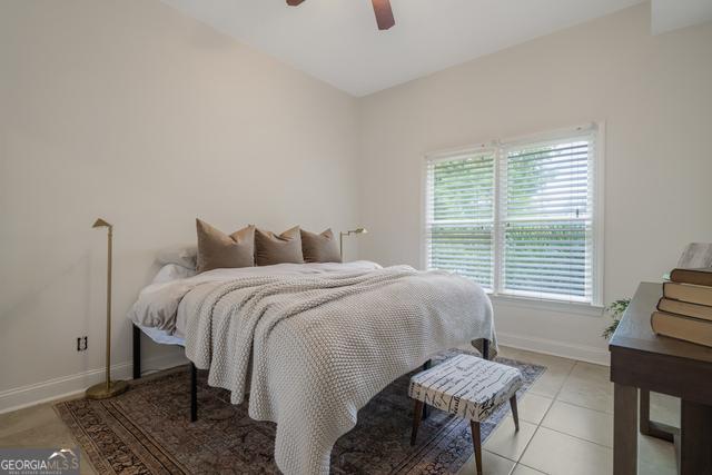 bedroom featuring light tile patterned floors, a ceiling fan, and baseboards