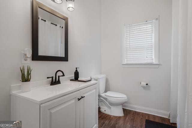 full bathroom featuring toilet, wood finished floors, vanity, and baseboards