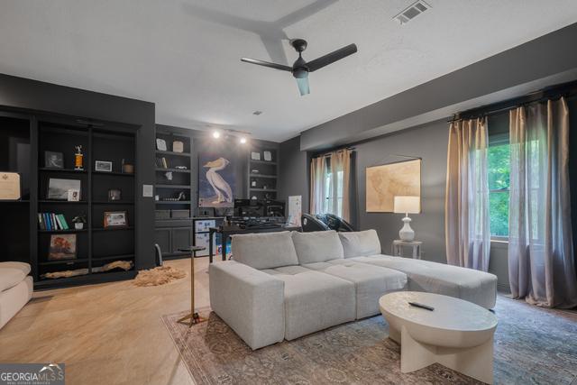 living area with built in shelves, visible vents, and a ceiling fan