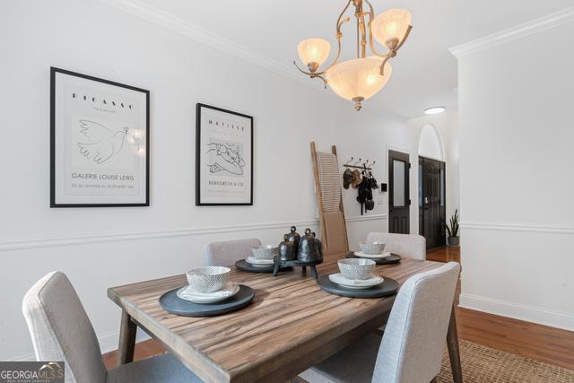 dining room featuring a chandelier, baseboards, wood finished floors, and crown molding