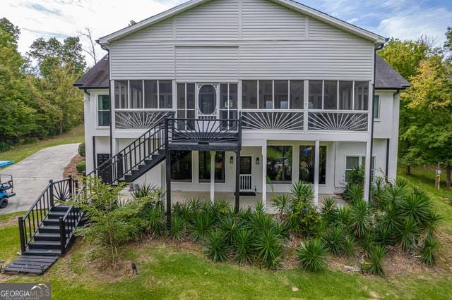 rear view of property featuring a sunroom, a patio area, and stairs