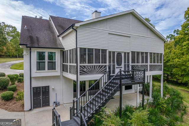 rear view of property with a sunroom, stairs, a chimney, and a patio