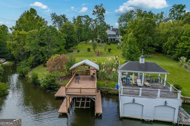 view of dock with a water view, a lawn, and a gazebo