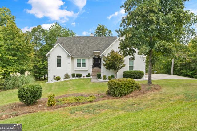 view of front facade featuring driveway, a chimney, and a front lawn