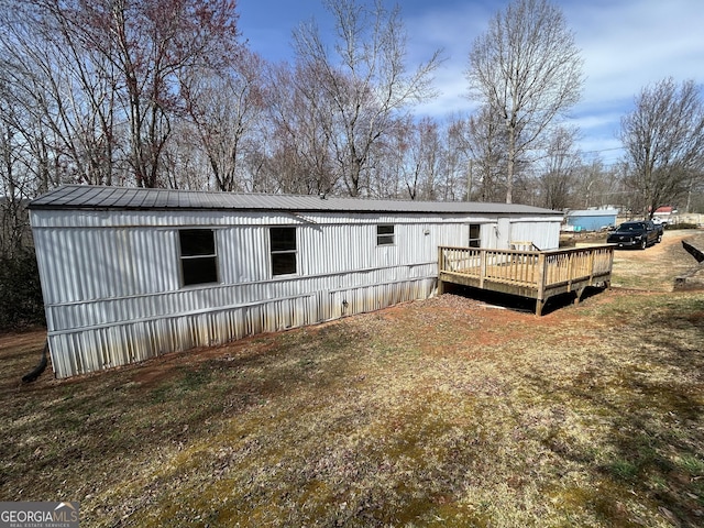 back of property featuring a deck and metal roof