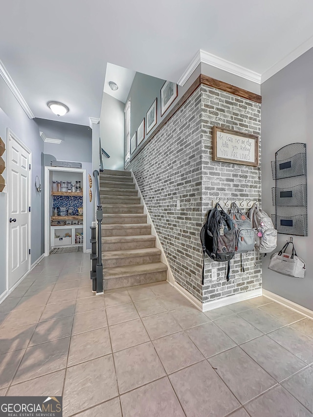 stairs with brick wall, ornamental molding, and tile patterned flooring