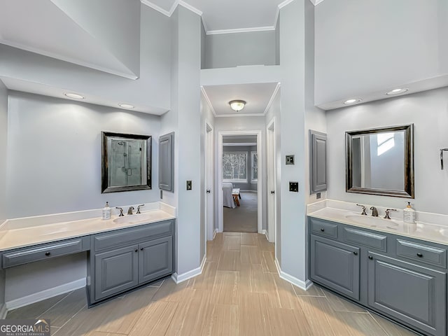 ensuite bathroom featuring crown molding, two vanities, a sink, and baseboards