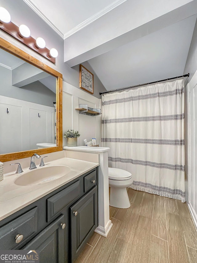 bathroom featuring toilet, wood finished floors, vaulted ceiling, crown molding, and vanity