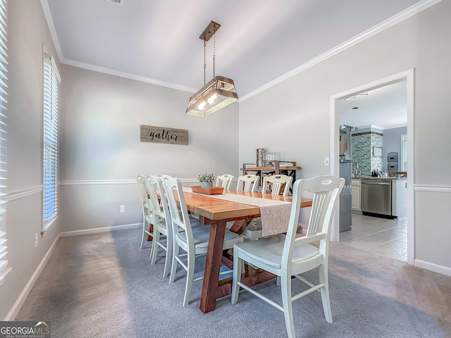 dining room featuring light carpet, crown molding, and baseboards