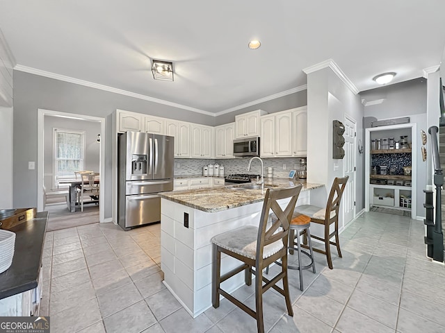 kitchen featuring tasteful backsplash, appliances with stainless steel finishes, light stone counters, a peninsula, and a sink