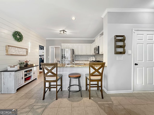 kitchen with light tile patterned floors, a peninsula, a breakfast bar, appliances with stainless steel finishes, and decorative backsplash