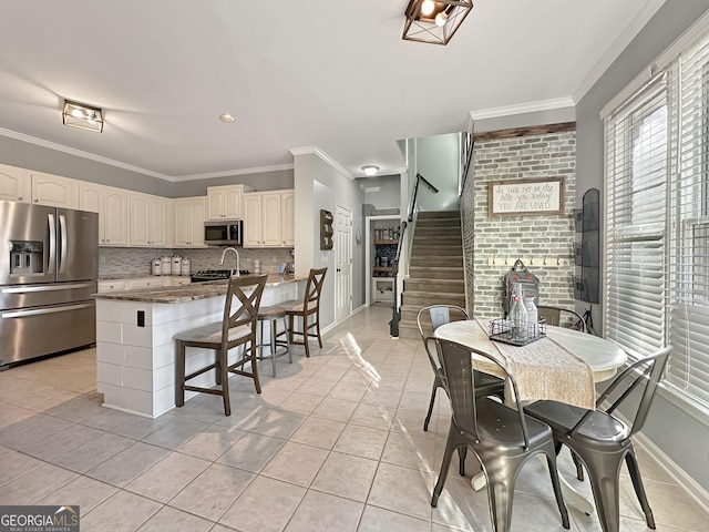 kitchen with stainless steel appliances, a breakfast bar area, backsplash, and crown molding